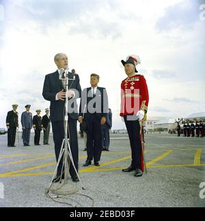 Reise nach Bermuda: Ankunft auf der Kindley Air Force Base, Bermuda, 12:55pm Uhr. Premierminister von Großbritannien Harold Macmillan spricht die Menschenmenge über Präsident John F. Kennedyu2019s Ankunft in Bermuda von Palm Beach, Florida. Präsident Kennedy und der Gouverneur von Bermuda, Generalmajor Sir Julian Gascoigne, stehen rechts. Kindley Air Force Base, St. Davidu2019s Island, Bermuda. Stockfoto