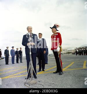 Reise nach Bermuda: Ankunft auf der Kindley Air Force Base, Bermuda, 12:55pm Uhr. Premierminister von Großbritannien Harold Macmillan spricht die Menschenmenge über Präsident John F. Kennedyu2019s Ankunft in Bermuda von Palm Beach, Florida. Präsident Kennedy und der Gouverneur von Bermuda, Generalmajor Sir Julian Gascoigne, stehen rechts. Kindley Air Force Base, St. Davidu2019s Island, Bermuda. Stockfoto