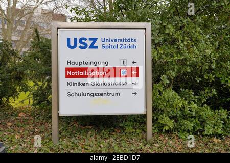 Wegweiser Notaufnahme oder E.R. Richtung Universitätsklinikum Zürich mit dem Gebäude selbst im Hintergrund. Die Wegbeschreibung ist in deutscher Sprache. Stockfoto