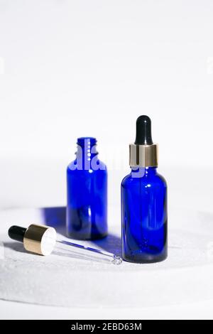 Blaue Glas Tropfflasche auf weißem Hintergrund mit schwarz Und goldene Kappen Beauty-Industrie Hautpflege und Behandlung schöne Zusammensetzung Stockfoto