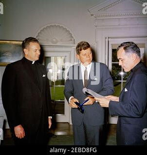 Übergabe der Laetare-Medaille Notre Dameu0027s an Präsident Kennedy, 1:25pm Uhr. Reverend Theodore M. Hesburgh (rechts), Präsident der University of Notre Dame, hält eine Rede bei der Verleihung der Laetare-Medaille für 1961 von der University of Notre Dame an Präsident John F. Kennedy. Pater Edmund P. Joyce, Vizepräsident der Universität Notre Dame, schaut zu. Oval Office, White House, Washington, D.C. Stockfoto