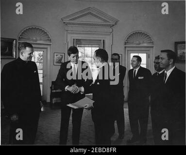 Übergabe der Laetare-Medaille Notre Dameu0027s an Präsident Kennedy, 1:25pm Uhr. Präsident John F. Kennedy wird von der University of Notre Dame die Laetare-Medaille für 1961 verliehen. Teilnahme an der Präsentation (L-R): Pater Edmund P. Joyce, Vizepräsident der University of Notre Dame; Präsident Kennedy; Reverend Theodore M. Hesburgh, Präsident der University of Notre Dame; drei unbekannte Männer; und Vertreter John Brademas (Indiana). Oval Office, White House, Washington, D.C. Stockfoto