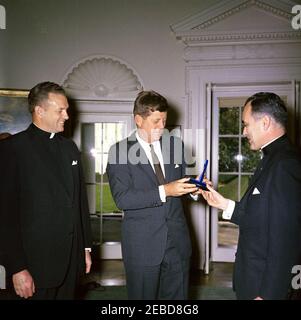 Übergabe der Laetare-Medaille Notre Dameu0027s an Präsident Kennedy, 1:25pm Uhr. Reverend Theodore M. Hesburgh (rechts) überreicht Präsident John F. Kennedy die Laetare-Medaille für 1961 von der University of Notre Dame. Pater Edmund P. Joyce, Vizepräsident der Universität Notre Dame, schaut zu. Oval Office, White House, Washington, D.C. Stockfoto