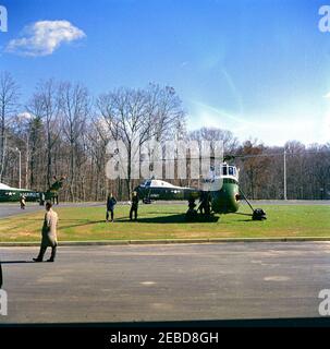 Übergabe der National Security Medal an Allen Dulles, 11:00am Uhr. Präsident John F. Kennedy kommt mit einem Hubschrauber der US-Armee im Hauptquartier der Central Intelligence Agency (CIA) in Langley, Virginia, an, um Allen W. Dulles, dem scheidenden Direktor der CIA, die National Security Medal zu präsentieren. Präsident Kennedy geht über eine Rasenfläche und wird von Naval Aide zum Präsidenten Kapitän Tazewell Shepard (zu Fuß direkt hinter dem Präsidenten) begleitet. Stockfoto