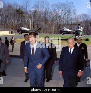 Übergabe der National Security Medal an Allen Dulles, 11:00am Uhr. Präsident John F. Kennedy kommt am Hauptquartier der Central Intelligence Agency (CIA) in Langley, Virginia, an, um Allen W. Dulles, dem scheidenden Direktor der CIA, die National Security Medal zu präsentieren. Präsident Kennedy geht mit Mr. Dulles (rechts). Dahinter folgen (L-R): Verteidigungsminister Robert S. McNamara, United States Army General Maxwell D. Taylor und Naval Aide to the President Captain Tazewell Shepard. Hubschrauber der United States Army sind im Hintergrund zu sehen. Stockfoto