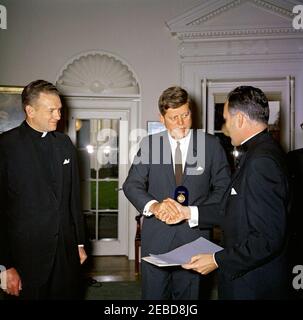 Übergabe der Laetare-Medaille Notre Dameu0027s an Präsident Kennedy, 1:25pm Uhr. Reverend Theodore M. Hesburgh (rechts) überreicht Präsident John F. Kennedy die Laetare-Medaille für 1961 von der University of Notre Dame. Pater Edmund P. Joyce, Vizepräsident der Universität Notre Dame, schaut zu. Oval Office, White House, Washington, D.C. Stockfoto