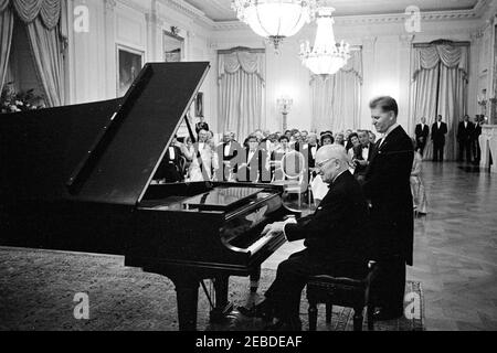 Abendessen zu Ehren des ehemaligen Präsidenten Harry S. Truman (HST), 8:00pm Uhr. Der ehemalige Präsident Harry S. Truman spielt zu seinen Ehren bei einem Abendessen Klavier. Der Pianist Eugene List steht hinter Präsident Truman. Sitzend, erste Reihe (L-R): Kongressabgeordneter Richard W. Bolling von Missouri (teilweise versteckt), ehemalige First Lady Bess Truman, Präsident John F. Kennedy, First Lady Jacqueline Kennedy und Vizepräsident Lyndon B. Johnson. Ebenfalls auf dem Foto zu sehen sind Margaret Truman Daniel, ehemalige Staatssekretärin und Beraterin von Präsident Kennedy Dean Acheson, ehemaliger Senator Scott W. Lucas (Illinois), Roberta Vinson, Pres Stockfoto