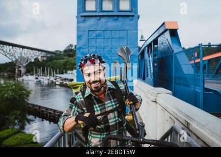 Ein hübscher junger Mann hält Fahrrad auf der Schulter und lächelt Stockfoto