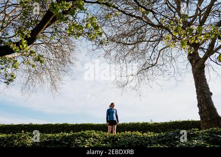 Die junge Frau steht und sieht die Ansicht mit Laufen an Shorts Stockfoto