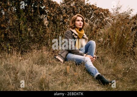 Porträt einer jungen Frau trägt Pullover auf der sitzen Gras Stockfoto