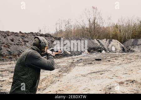 Ein Kerl schießt von einem Jagdgewehr auf die Schießerei Bereich in der Wüste Sportschießen Stockfoto