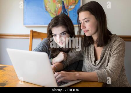 Zwei junge kaukasische Frauen arbeiten zusammen an einem Laptop Stockfoto