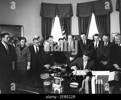 Bill Signing - H.R. 7500 Öffentliches Recht 87-293, Peace Corps Act, 9:45am. Präsident John F. Kennedy unterzeichnet HR 7500, das Peace Corps Bill, im Oval Office, White House, Washington, D.C., mit Blick auf (L-R): Direktor des Peace Corps, R. Sargent Shriver; Senator Philip A. Hart von Michigan (im Rücken); Vertreter Edna Kelly von New York; Vertreter Chester Merrow von New Hampshire; Vertreter Thomas F. Johnson von Maryland; Vertreter Clement Zablocki von Wisconsin; Vertreter Wayne L. Hays von Ohio; Vertreter Roman C. Pucinski von Illinois; Senator Hubert H. Humphrey von Minnesota; R Stockfoto