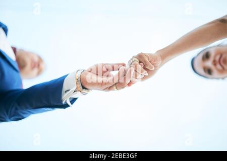 Frisch verheiratetes Paar, das die Hände in einer Bottom-up-Position hält Stockfoto