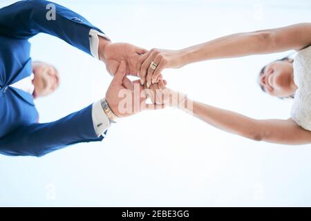 Frisch verheiratetes Paar, das die Hände in einer Bottom-up-Position hält Stockfoto