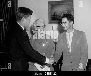 Ankündigung der ersten öffentlichen Wohnungen für Inder, 11:42am. Präsident John F. Kennedy kündigt die erste öffentliche Wohnungsplanung für eine indische (Native American) Reservation, Oval Office, White House, Washington, D.C. Präsident Kennedy gratuliert dem Oglala Sioux Stamm der Pine Ridge Reservation in South Dakota und der Oglala Sioux Housing Authority. (L-R) Präsident Kennedy; Kommissarin für den öffentlichen Wohnungsbau Marie McGuire; Chief Johnson Holy Rock vom Stamm Oglala Sioux. Stockfoto