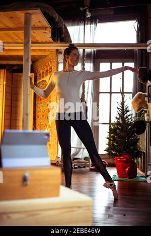 Ballerina übt Bar Ballett auf Zoom Video-Klasse zu Hause Im Winter Stockfoto