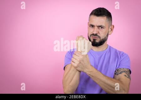 Junge gutaussehende Mann trägt lässige T-Shirt über rosa Hintergrund leiden Schmerzen an Händen und Fingern, Arthritis Entzündung Stockfoto