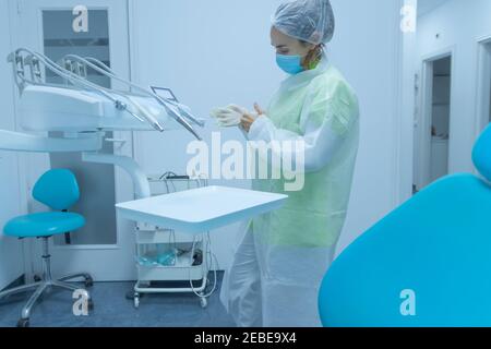 Frau Zahnarzt in Schutzkleidung setzen auf Handschuhe, Zahnklinik Stockfoto