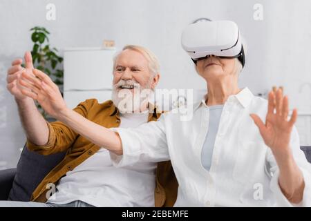 Ältere Frau mit vr-Headset in der Nähe fröhlichen Ehemann Stockfoto