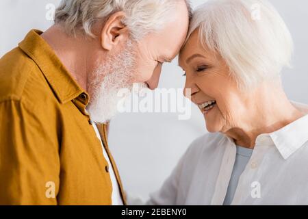 Fröhliche ältere Frau, die zu Hause neben dem Mann steht Stockfoto