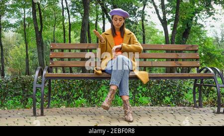 Beleidigte Frau Überprüfung Zeit während der Wartezeit auf Bank im Herbst parken Stockfoto