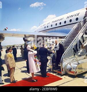 Ankunftzeremonien für Habib Bourguiba, Sr., Präsident von Tunesien, und Frau Moufida Bourguiba, 12:00pm Uhr. Ankunftszeremonien für Habib Bourguiba, Sr., Präsident von Tunesien. Präsident John F. Kennedy begrüßt den Präsidenten Tunesiens, Habib Bourguiba, Sr., als er aus dem Flugzeug steigt; Militärhilfe für den Präsidenten, General Chester V. Clifton, und First Lady Jacqueline Kennedy stehen links; First Lady von Tunesien, Moufida Bourguiba (früher Mathilde Lorrain), steht oben auf einer Treppe. Military Air Transport Service (MATS) Terminal, Washington National Airport, Washington, D.C. Stockfoto