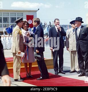 Ankunftzeremonien für Habib Bourguiba, Sr., Präsident von Tunesien, und Frau Moufida Bourguiba, 12:00pm Uhr. Ankunftszeremonien für Habib Bourguiba, Sr., Präsident von Tunesien. Links spricht der Militärdienst des Präsidenten, General Chester V. Clifton, mit First Lady Jacqueline Kennedy und Präsident John F. Kennedy. Der stellvertretende Chef des Protokolls für Besuche und öffentliche Veranstaltungen, Samuel L. King, steht an dritter Stelle von rechts; der Assistent der Air Force Aide des Präsidenten, Major Frank S. Evans, steht an zweiter Stelle von rechts (teilweise versteckt). Andere sind nicht identifiziert. Militärischer Luftverkehrsdienst (MATS) Terminal Stockfoto