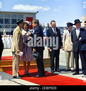 Ankunftzeremonien für Habib Bourguiba, Sr., Präsident von Tunesien, und Frau Moufida Bourguiba, 12:00pm Uhr. Ankunftszeremonien für Habib Bourguiba, Sr., Präsident von Tunesien. Links spricht der Militärdienst des Präsidenten, General Chester V. Clifton, mit First Lady Jacqueline Kennedy und Präsident John F. Kennedy. Der stellvertretende Chef des Protokolls für Besuche und öffentliche Veranstaltungen, Samuel L. King, steht in der Mitte; der Assistent der Air Force Aide des Präsidenten, Major Frank S. Evans, steht an zweiter Stelle von rechts. Andere sind nicht identifiziert. Military Air Transport Service (MATS) Terminal, Washington National Airp Stockfoto