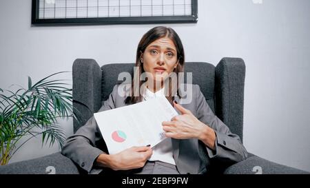 Verärgert Geschäftsfrau halten Dokument und Blick auf Kamera auf Sessel Stockfoto