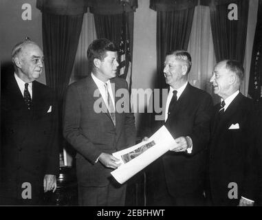 Treffen mit Mitgliedern der American Battle Monuments Commission (ABC), 12:17pm Uhr. Vertreter der American Battle Monuments Commission (ABC) zeigen Präsident John F. Kennedy ein Foto des Manila American Cemetery and Memorial of Global City, Taguig, Phillippines, im Oval Office, White House, Washington, D.C. (L-R) ABC Vice Chairman Admiral Thomas Cassin Kinkaid; Präsident Kennedy; ABMC-Vorsitzender Jacob u0022Jakeu0022 Loucks Devers; Senior Member von ABMC und ehemalige Senatssekretärin Leslie L. Biffle. Stockfoto