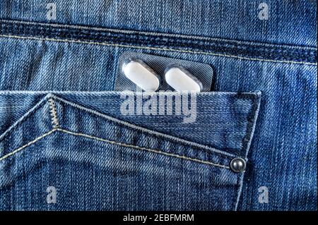 Pillen in der Jeans-Tasche. Blisterpackung mit weißen Pillen in der Gesäßtasche. Gesundheitskonzept Stockfoto