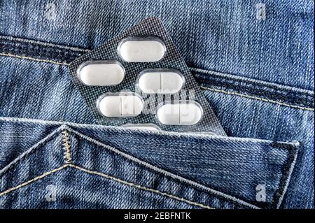 Pillen in der Jeans-Tasche. Blisterpackung mit weißen Pillen in der Gesäßtasche. Gesundheitskonzept Stockfoto