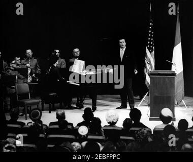 Zeremonie zur Feier der Vereinigung Italiens, 10:31am Uhr. Zeremonie zur Feier der Vereinigung Italiens. Mehrere nicht identifizierte Mitglieder der United States Marine Band; nicht identifizierter Klavierspieler; Opernsänger Franco Corelli; in der ersten Publikumsreihe sitzend (von der Kamera weggewandt), First Lady Jacqueline Kennedy (rechts, mit weißem Hut). State Department Auditorium, Washington, D.C., rnrn Stockfoto