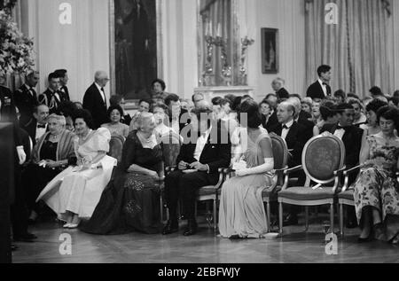 Abendessen zu Ehren der Nobelpreisträger, 8:00pm Uhr. Präsident John F. Kennedy und andere treffen sich im East Room, um bei einer Lesung des Schauspielers Frederic March von Auszügen aus den Werken der späten amerikanischen Nobelpreisträger während eines Abendessens zu Ehren der Nobelpreisträger aus der westlichen Hemisphäre teilzunehmen. Präsident Kennedy und First Lady Jacqueline Kennedy besuchen mit der Nobelpreisträgerin Pearl S. Buck. Platz in der ersten Reihe (L-R): Vizepräsident Lyndon B. Johnson (meist versteckt); Katherine Tupper Marshall (Witwe des Nobelpreisträgers und ehemaligen Staatssekretärs, General George C. Marshall); Lady Bird Stockfoto