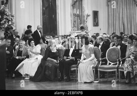 Abendessen zu Ehren der Nobelpreisträger, 8:00pm Uhr. Präsident John F. Kennedy und andere treffen sich im East Room, um bei einer Lesung des Schauspielers Frederic March von Auszügen aus den Werken der späten amerikanischen Nobelpreisträger während eines Abendessens zu Ehren der Nobelpreisträger aus der westlichen Hemisphäre teilzunehmen. Präsident Kennedy und First Lady Jacqueline Kennedy besuchen mit der Nobelpreisträgerin Pearl S. Buck. Platz in der ersten Reihe (L-R): Vizepräsident Lyndon B. Johnson (meist versteckt); Katherine Tupper Marshall (Witwe des Nobelpreisträgers und ehemaligen Staatssekretärs, General George C. Marshall); Lady Bird Stockfoto