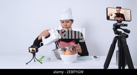Food-Blogger. Asiatische Frau Koch Streaming live. Sie kommunizieren mit Abonnenten über Telefon-Kamera online. Vlogger und Online-Influencer Aufnahme Stockfoto