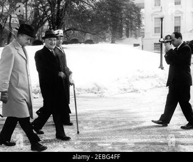 Treffen mit dem ehemaligen Präsidenten Harry S. Truman (HST), 10:02am Uhr. Der Kameramann filmt den ehemaligen Präsidenten Harry S. Truman, als er im Weißen Haus ankommt, um Präsident John F. Kennedy zu treffen. Präsident Truman wird von Marinehelfer, Kapitän Cooper B. Bright (Dritter von links), und einem unbekannten Helfer begleitet. Washington, D.C. Stockfoto