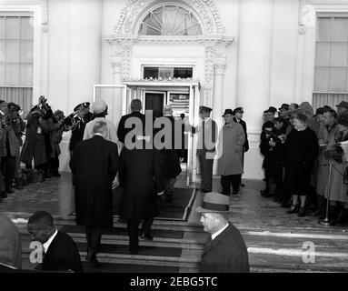 Zeremonien vor der Eröffnung im Weißen Haus. Vor der Eröffnungszeremonie begleitet der Präsident Dwight D. Eisenhower den designierten Präsidenten John F. Kennedy und seine Frau Jacqueline Kennedy ins Weiße Haus. Senator John J. Sparkman von Alabama geht die Treppe auf der linken Seite hinauf. Militärdienst an Präsident Eisenhower Oberst Robert L. Schulz begrüßt links und Luftwaffenstützer an Präsident Eisenhower Oberst William G. Draper steht rechts in der Mitte des Salutes. White House Secret Service Agent Floyd Boring steht im Vordergrund (Mitte rechts). Stockfoto