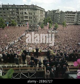 Europa-Reise: Deutschland, West-Berlin, Präsident Kennedy spricht im Rathaus Schu00f6neberg, 12:50pm Uhr. Präsident John F. Kennedy (am Rednerpult im Vordergrund, zurück zur Kamera) hält Bemerkungen vor einer Menschenmenge am Rudolph Wilde Platz in West-Berlin (Bundesrepublik). Präsident Kennedy hielt seine Rede von einer Plattform, die auf den Stufen des West Berlinu2019s Rathauses, Rathaus Schu00f6neberg, errichtet wurde. Bundeskanzler Konrad Adenauer und Dolmetscher für das deutsche Außenministerium Heinz Weber stehen rechts vom Präsidenten; Bürgermeister Willy Brandt, st Stockfoto