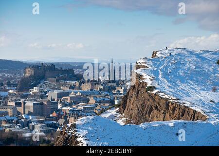 Blick auf die schneebedeckten Salisbury Crags im Winter im Holyrood Park mit Edinburgh Castle im Hintergrund, Edinburgh, Schottland, Großbritannien Stockfoto