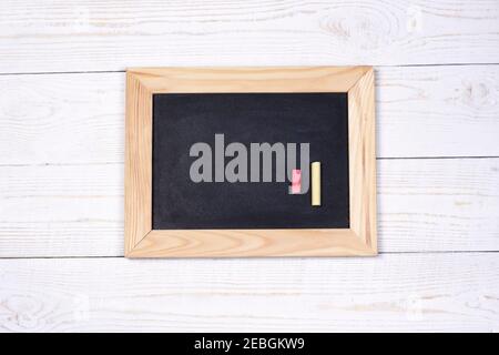 Tafel und Kreiden auf weißem Holzhintergrund mit Platz für Text flach legen, Draufsicht, mockup. Stockfoto