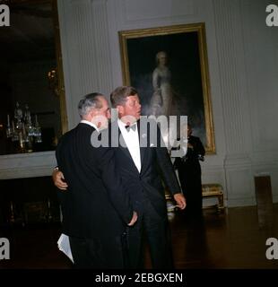 Abendessen zu Ehren der Nobelpreisträger, 8:00pm Uhr. Präsident John F. Kennedy besucht den Schauspieler Frederic March (Mitte links) bei einem Abendessen zu Ehren der Nobelpreisträger aus der westlichen Hemisphäre; Herr March führte zu diesem Anlass eine Lesung vor. Ein nicht identifizierter Fotograf steht im Hintergrund. East Room, White House, Washington, D.C. Stockfoto