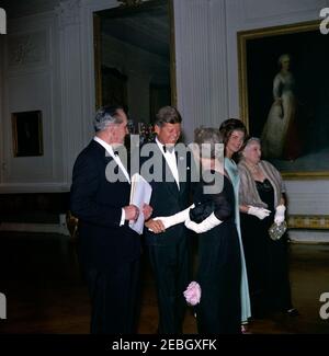 Abendessen zu Ehren der Nobelpreisträger, 8:00pm Uhr. Präsident John F. Kennedy besucht mit Gästen den East Room während eines Abendessens zu Ehren der Nobelpreisträger aus der westlichen Hemisphäre. Von links nach rechts: Schauspieler, Frederic March; Präsident Kennedy; Schriftstellerin Mary Welsh Hemingway (Witwe des Nobelpreisträgers Ernest Hemingway), dem Präsidenten die Hände schüttelnd; First Lady Jacqueline Kennedy und Katherine Tupper Marshall (Witwe des Nobelpreisträgers und ehemaligen Staatssekretärs, General George C. Marshall). White House, Washington, D.C. Stockfoto