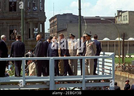 Europareise: Deutschland, West-Berlin: Präsident Kennedy am Checkpoint Charlie, 12:05pm Uhr. Präsident John F. Kennedy blickt von einer erhöhten Plattform am Checkpoint Charlie entlang der Berliner Mauer in West-Berlin (Bundesrepublik) auf Ost-Berlin, DDR (Demokratische Republik). Ebenfalls im Bild: Bundeskanzler Konrad Adenauer; Oberbürgermeister Willy Brandt; Botschafter der Bundesrepublik Deutschland in den USA, Karl Heinrich Knappstein; Bundesminister Dr. Rainer Barzel; Generalkommandierender der Berliner Brigade, Generalmajor Frederick O. Hartel; Militärdienst Stockfoto