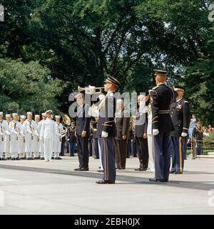 Memorial Day Zeremonien auf dem Nationalfriedhof von Arlington, 10:50am Uhr. Präsident John F. Kennedy und andere hören während der Memorial Day Zeremonien auf dem Arlington National Cemetery in Arlington, Virginia, einem Spieler zu. Der Verwalter der Veterans Administration (VA), General John S. Gleason (Gesicht verdeckt) und der ehemalige Botschafter der Vereinigten Staaten in Irland, Grant Stockdale, stehen rechts vom Bugler; Seemänner der United States Navy stehen links im Hintergrund. Stockfoto