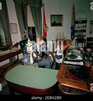 Präsident Kennedy mit Caroline Kennedy (CBK) u0026 John F. Kennedy, Jr. (JFK, Jr.), in Halloween-Kostümen. Präsident John F. Kennedy lacht, als seine Kinder Caroline Kennedy (links, mit einer Katze) und John F. Kennedy, Jr., ihre Halloween-Kostüme modellieren. Oval Office, White House, Washington, D.C. Stockfoto