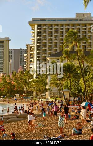 Menschen entspannen und sonnen am Waikiki Beach, umgeben von Resorts bei Sonnenuntergang, auf Oahu, Honolulu, Hawaii, USA Stockfoto