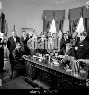 Bill Signing - H.R. 12 Öffentliches Recht 88-129, Gesundheitsberufe Bildungshilfe Gesetz von 1963, 9:40am. Präsident John F. Kennedy (sitzt am Schreibtisch) unterzeichnet den Health Professions Educational Assistance Act von 1963; ein nicht identifizierter Stenograf sitzt auf der linken Seite. Standing: Vertreter John E. Fogarty (Rhode Island); Leiter der Pädiatrie am Johns Hopkins Hospital, Dr. Robert E. Cooke; Senator Jacob K. Javits (New York); Unterstaatssekretär für Gesundheit, Bildung und Wohlfahrt (HEW), Ivan A. Nestingen (teilweise versteckt); Vertreter Claude Pepper (Florida); Senator John O. Pastore (Rhode Island); Direktor Stockfoto