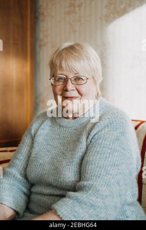 Nahaufnahme offen, authentische Porträt von Senior plus Größe blonde Frau zu Hause. Porträt einer reifen Frau mit Brille Stockfoto